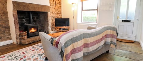 Ein gemütliches Wohnzimmer mit Kamin, Fernseher, einer Couch und einem gemusterten Teppich.