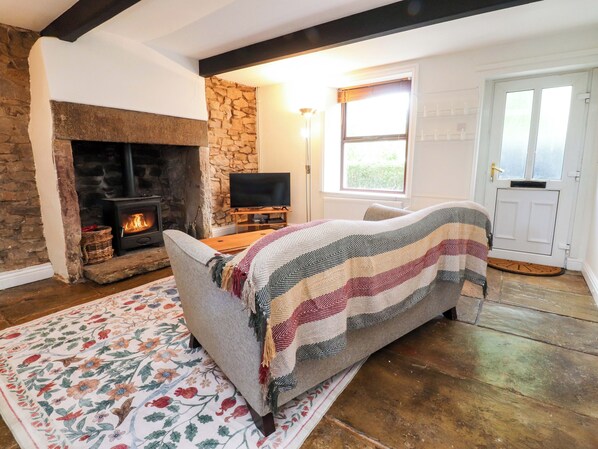 A cozy living room with a fireplace, a television, a sofa, and a patterned rug.