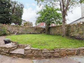 A stone wall, a grassy yard, and a tree.