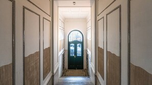Ein Korridor mit einer dunkelgrünen Tür, weißen Wänden und dekorativer Profilleiste.