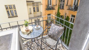 Ein Balkon mit rundem Tisch, einem Stuhl, einem Blumentopf und einer Kaffeetasse.
