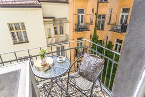 Ein Balkon mit rundem Tisch, einem Stuhl, einem Blumentopf und einer Kaffeetasse.