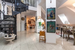 Ein geräumiger Loft mit einer schwarzen schmiedeeisernen Wendeltreppe, einem Essbereich mit Tisch und Stühlen sowie Kunstwerken an den Wänden.