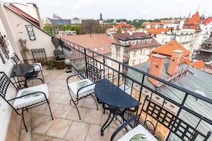 Ein Balkon mit Sitzgelegenheit, einer Uhr und Blick auf eine Stadtansicht.