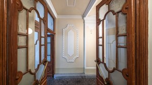 Un couloir avec deux portes en bois dotées de panneaux de verre, un panneau décoratif au mur et un sol en briques.