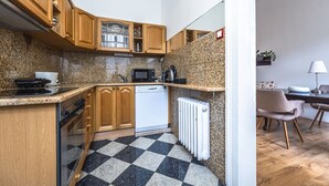 Une cuisine avec des meubles en bois, un four à micro-ondes, un lave-vaisselle et un carrelage à motifs carrés.