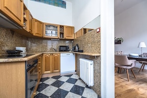 A kitchen with wooden cabinets, a microwave, a dishwasher, and a checkered floor. - Golden Prague Residence – Jáchymova Street (Prague)