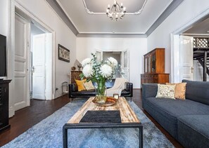 Ein Wohnzimmer mit einer Couch, einem Couchtisch mit einer Vase und einer Chandelier.