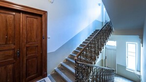 Une porte en bois, un escalier avec des rampes en métal ouvragé et une fenêtre laissant entrer la lumière naturelle.