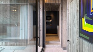 A modern interior with a glass door leading to a kitchen area. - Luxury Design in the Heart of Nature (Somme-Leuze)