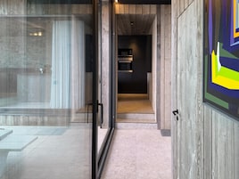 Un interior moderno con un vidrio que da a una zona de cocina.
