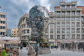 A modern building with a cylindrical glass facade, surrounded by other buildings with classical architecture. - Sweet & Cosy Old Town Apartment (Prague)