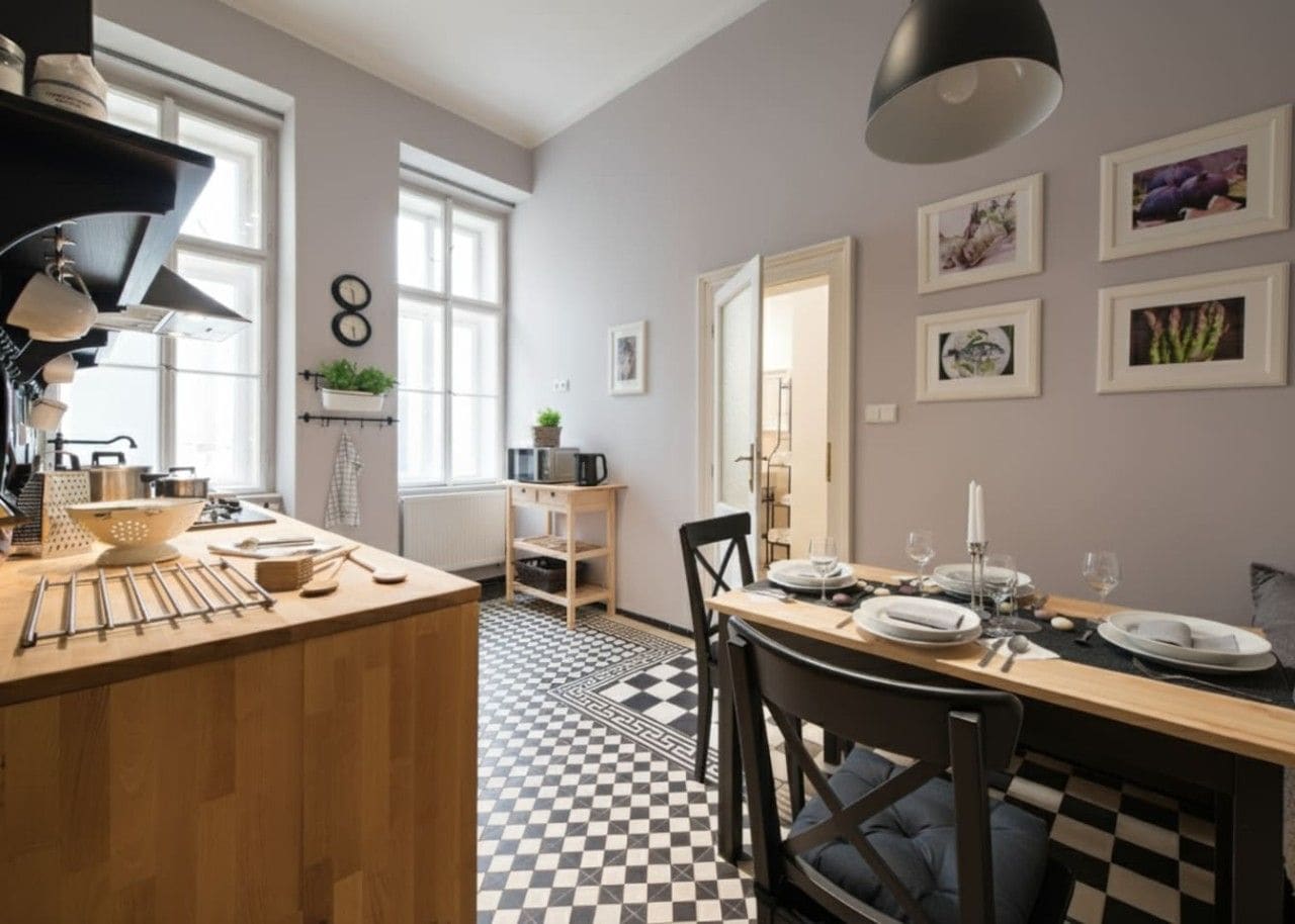 A modern kitchen with a checkered floor, wooden countertops, and a dining area with a table set for two.