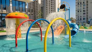 Una piscina con toboganes de colores y una fuente con forma de hongo.