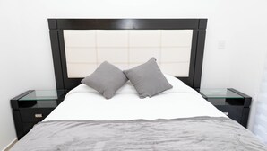 A bed with a headboard, two pillows, a blanket, and a bedside table with a glass top. - Gdl Sky Luxury residence (Zapopan)