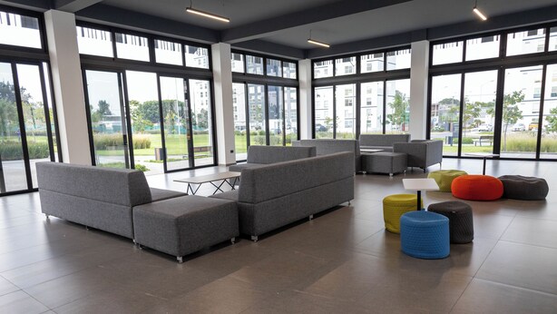 A spacious indoor area with large windows, grey sofas, and colorful stools. - Gdl Sky Luxury residence (Zapopan)