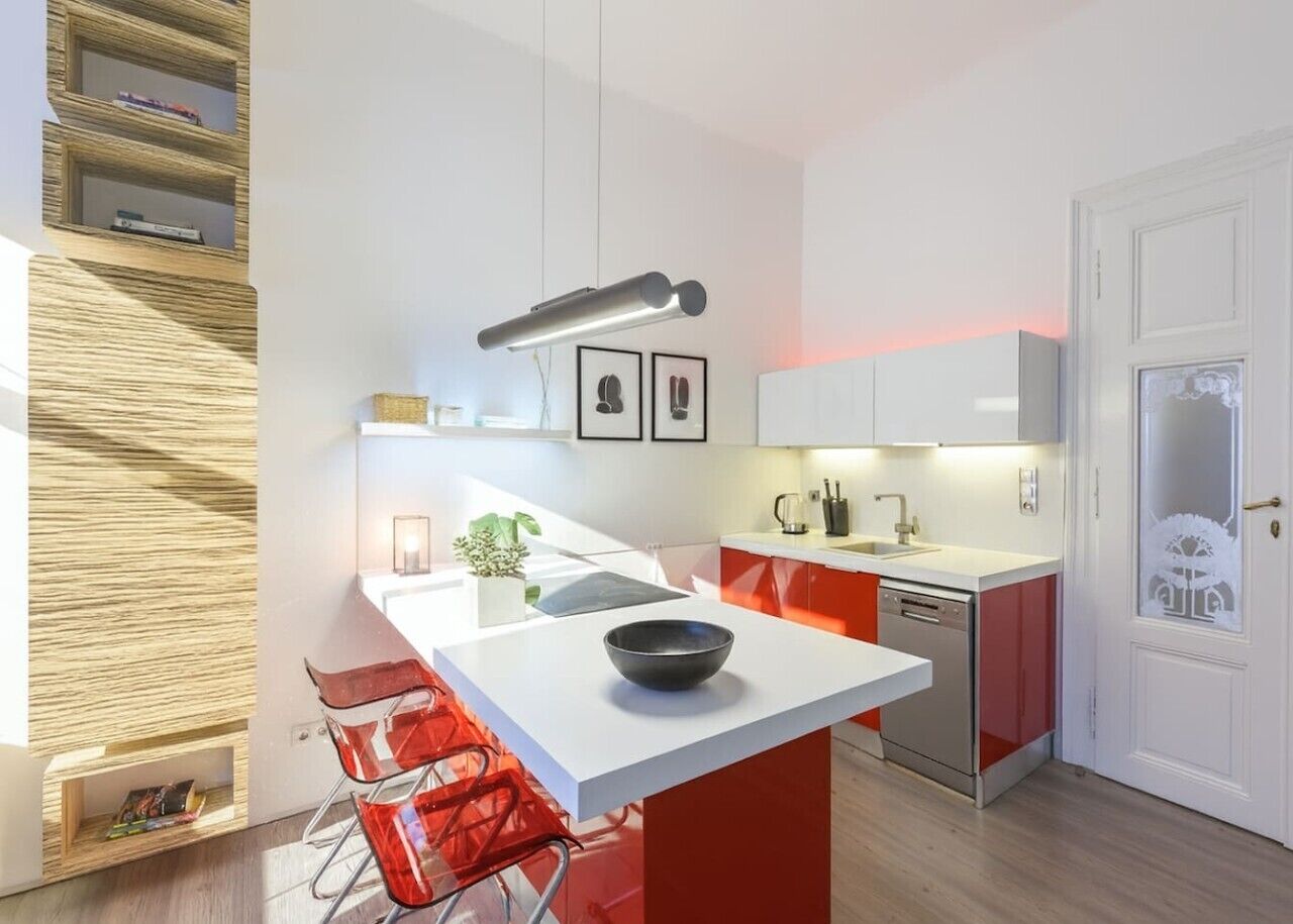 Una cocina moderna con una isla central, sillas rojas, lavavajillas y una puerta blanca con panel de vidrio esmerilado.