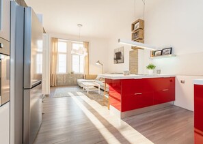 A modern kitchen with a central island, wooden flooring, and a built-in refrigerator. - Elegant Two-Bedroom Apartment in New Town (Prague)