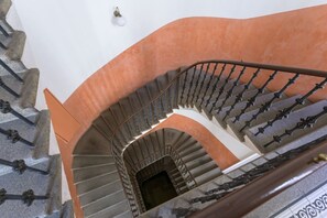 A spiral staircase with a curved design, metal balusters, and a white wall. - Elegant Two-Bedroom Apartment in New Town (Prague)