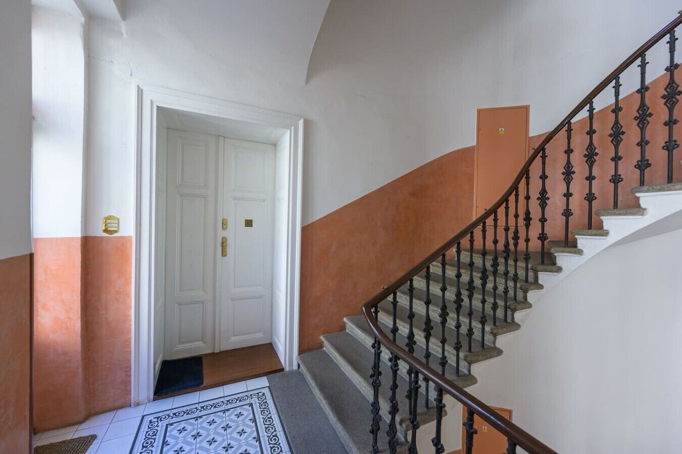 Uma escadaria com corrimão e uma porta na base.