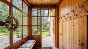 Interior de madera con ventanas amplias, un banco y una puerta con ganchos.