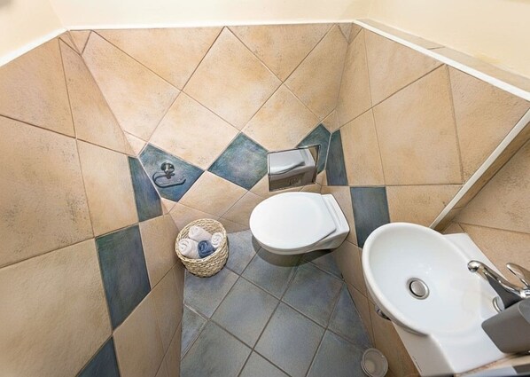 Ein Badezimmer mit Toilette, Waschbecken und einem kleinen Korb mit Handtüchern.