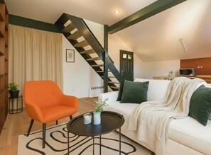 A modern living room with a staircase, a white sofa, an orange chair, and a small table with decorative items. - Old Town Penthouse with Prague Castle Views (Prague)