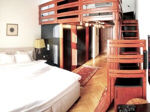 Ein Schlafzimmer mit einem Etagenbett, einem Nachttisch mit Lampe, einem roten Teppich und einer Holzleiter.
