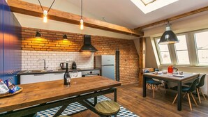 A kitchen with a brick wall, wooden beams, a dining area with a table and chairs, and a skylight. - Charles Bridge Loft Residence (Prague)