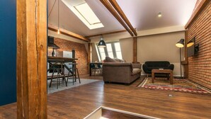 A loft-style living space with exposed wooden beams, a dining area with stools, a sofa, and a coffee table. - Charles Bridge Loft Residence (Prague)