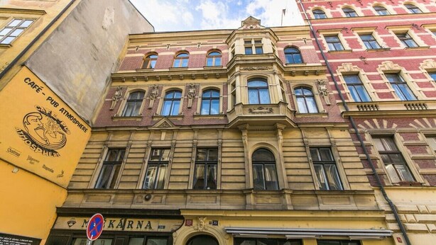 A multi-story building with a ground-floor shop named 'KARNA' and a cafe on the left. - Charles Bridge Loft Residence (Prague)