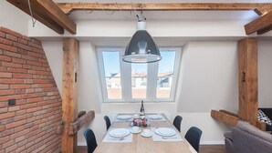 A dining area with a wooden table, chairs, a hanging light fixture, and a brick wall. - Charles Bridge Loft Residence (Prague)