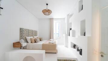 A minimalist bedroom with a bed, bedside tables, a hanging light fixture, and a window.