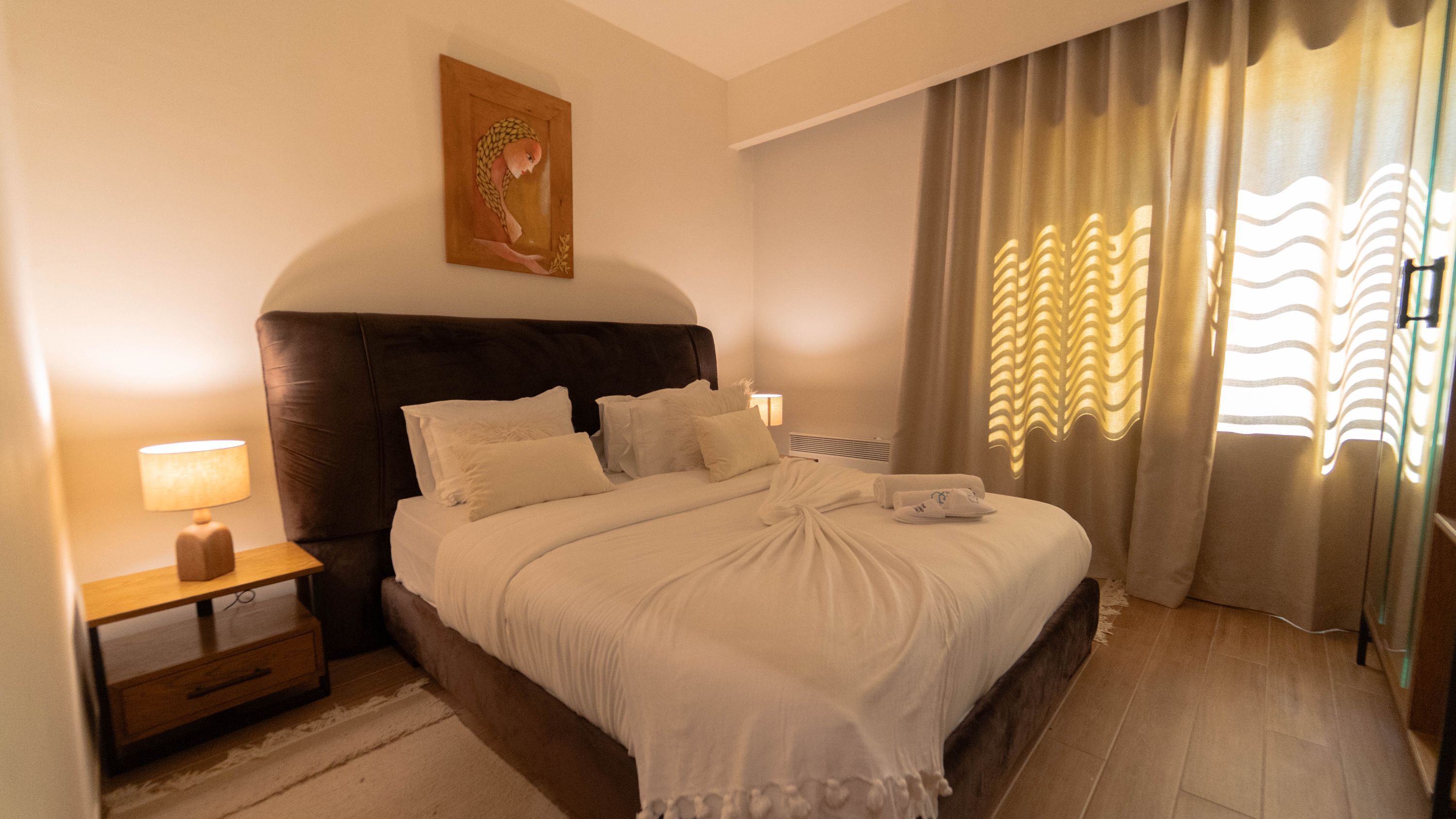 Une chambre d’hôtel avec un lit, une table de chevet, une lampe et des rideaux.
