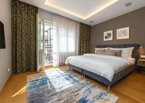 Ein modernes Schlafzimmer mit einem großen Bett, Blick ins Freie und einem gemusterten Vorhang.