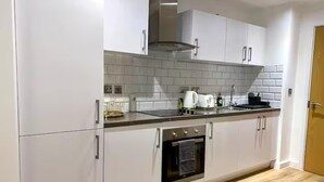 Una cocina moderna con armarios blancos, horno de acero inoxidable y salpicadero de azulejos.