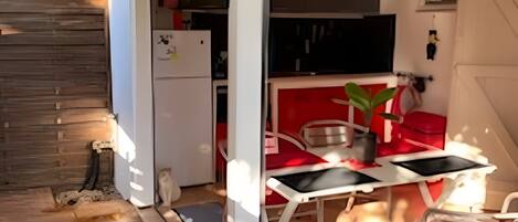 A covered patio with a dining area, a kitchen, and a wooden deck.