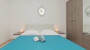 Quarto com cama, mesas de cabeceira, espelho e guarda-roupa.