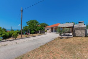 A residential area with a paved road, a stone house with a red roof, and a clear blue sky. - Villa Nina With Private Pool and Peacful Oasis (Imotski)