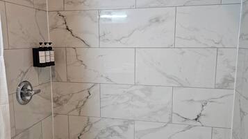 Un baño con bañera, ducha y azulejos de mármol.