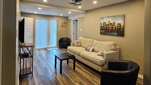 A living room with a sofa, a coffee table, a TV, and a painting on the wall.