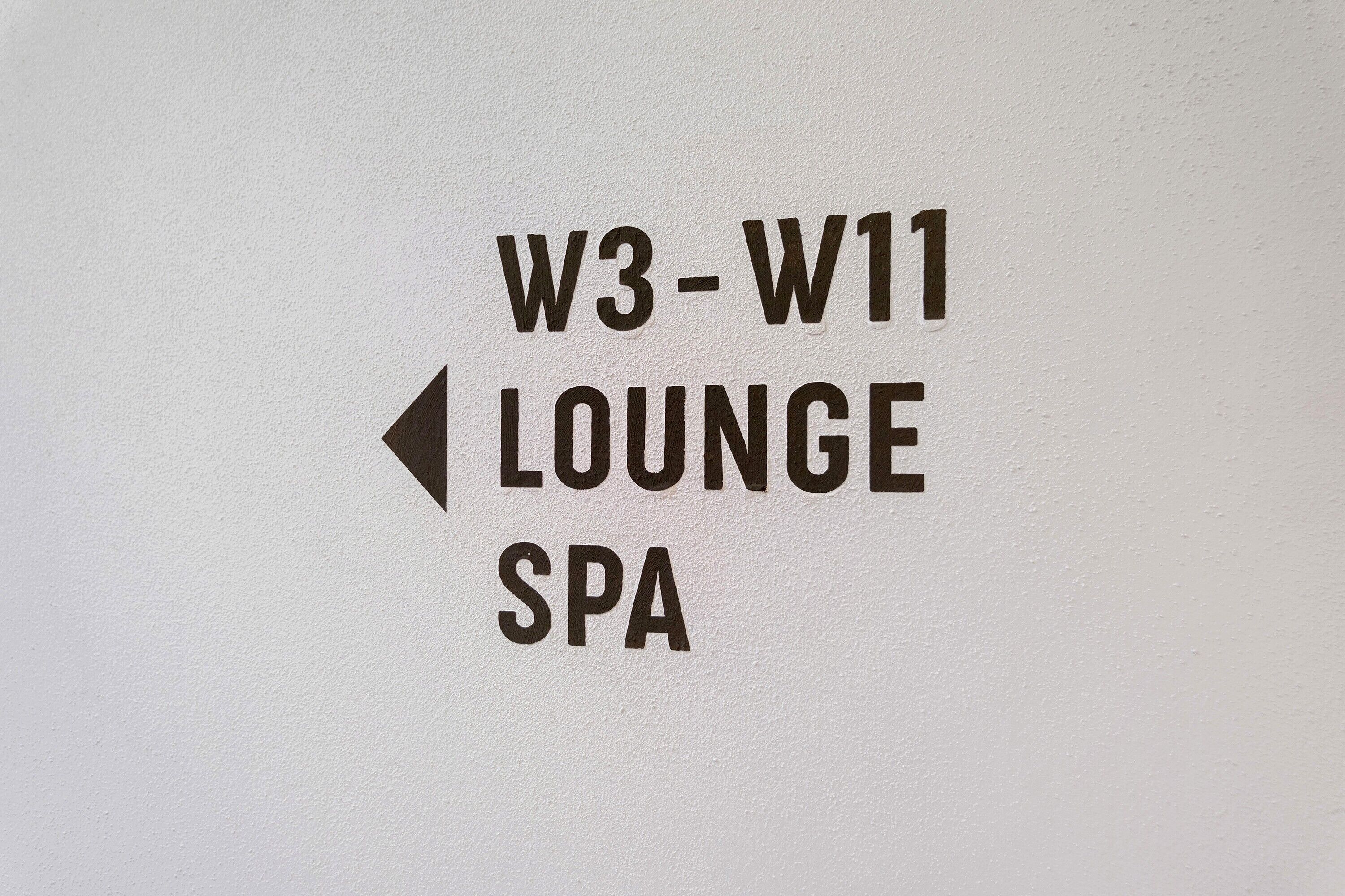 Ein Hinweisschild, das den Bereich für Lounge und Spa anzeigt, mit dem Text 'W3-W11 LOUNGE SPA' und einem nach links zeigenden Pfeil.