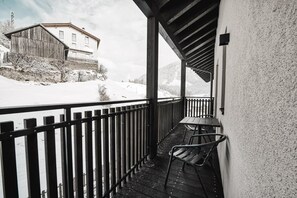 Un balcon avec une balustrade en bois, une table et deux chaises.
