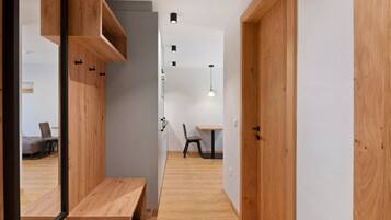 A hallway with wooden flooring, a bench, a table, and a chair.
