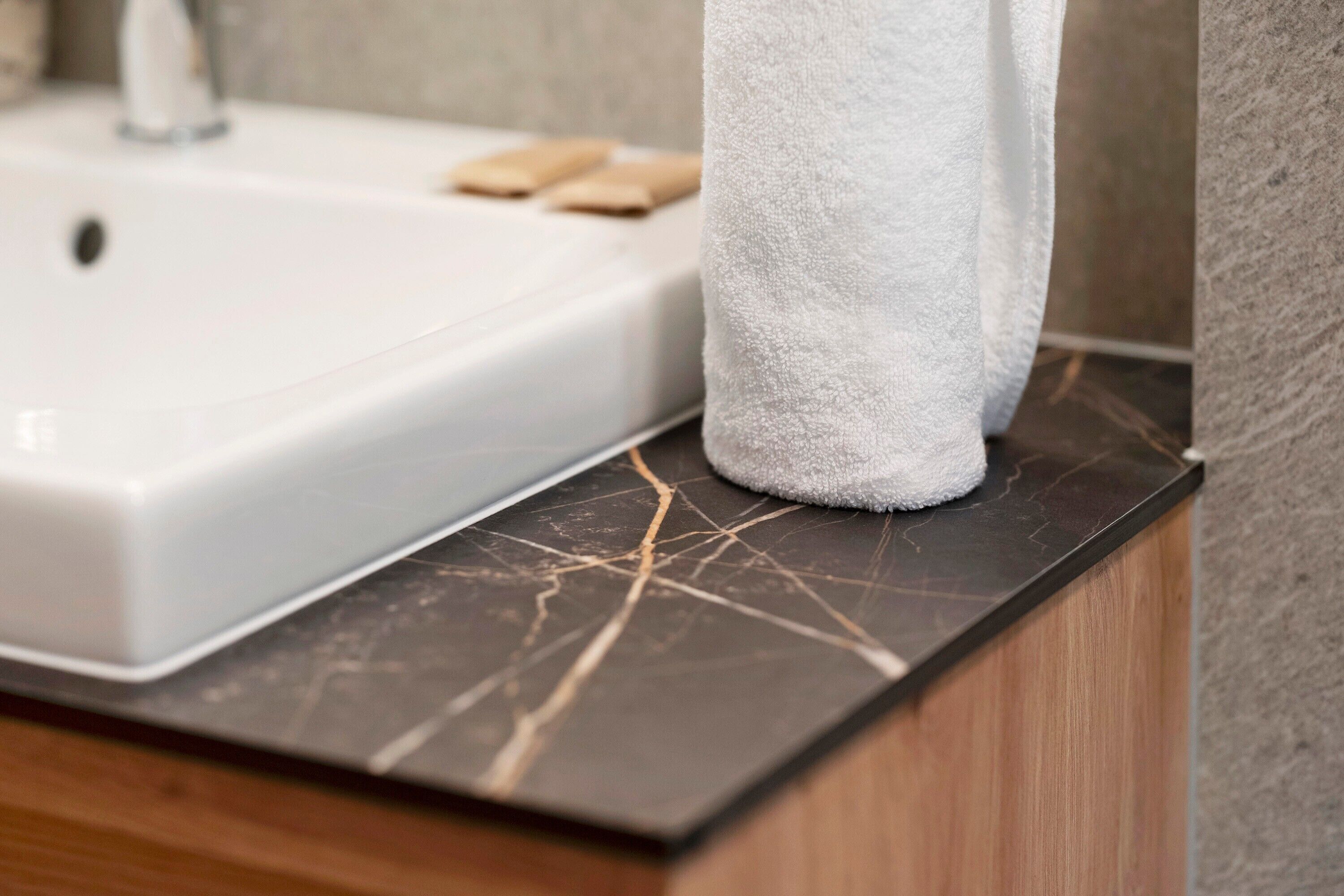 A bathroom sink with a marble countertop and a towel hanging on the wall.