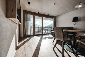 Ein modernes Zimmer mit Balkon, einem Esstisch und Stühlen.