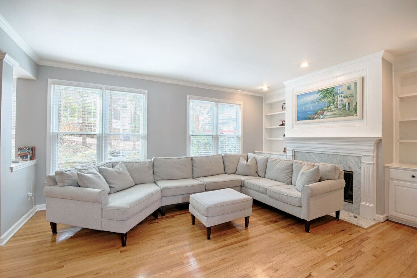 A living room with a sectional sofa, a fireplace, and large windows.