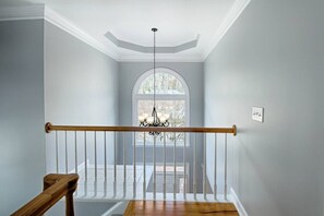 A staircase with a wooden handrail, white balusters, and a chandelier. - Spacious 4BR Near Lassiter | Game Room & Basement (Marietta)