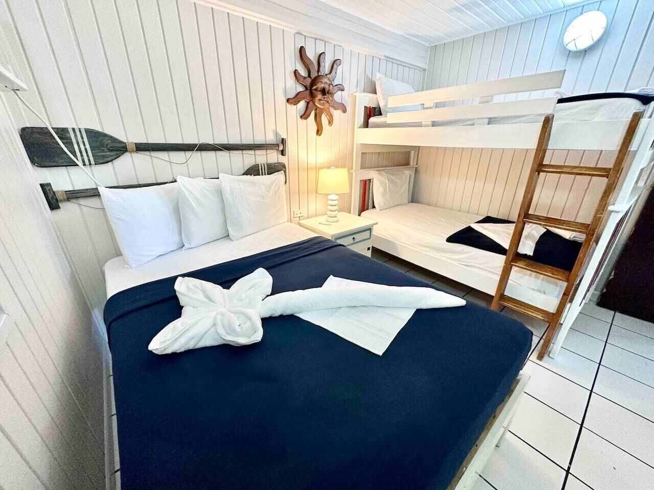 Ein Schlafraum mit Etagenbett, Nachttisch, Wanddeko und einer Holzleiter.