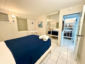 Une chambre d’hôtel comprenant un lit, une chaise, une armoire et une porte donnant sur un balcon.